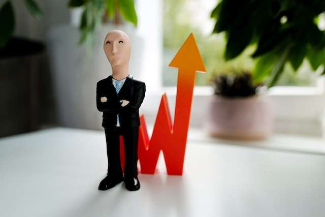 A businessman figurine in front of a graph pointing up, symbolic of better decisions with good books.