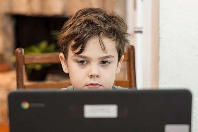 An unhappy boy looks at a computer, symbolic of bookkeeping software services.