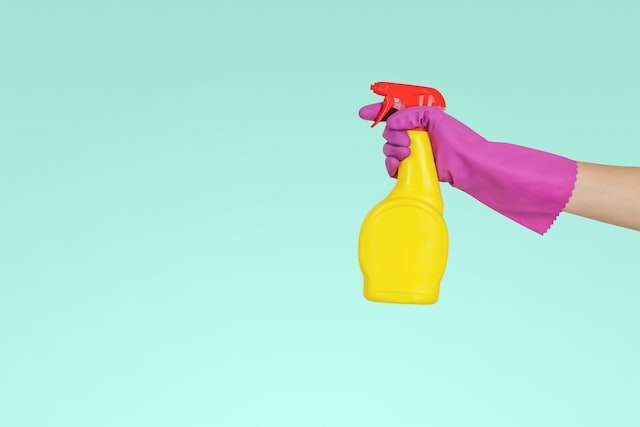 A hand holds a spray bottle, indicative of real estate bookkeeping catch ups and clean ups.