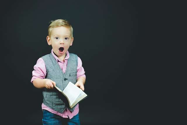 A child holding a book, symbolic of our SD payroll services managing child support withholdings.