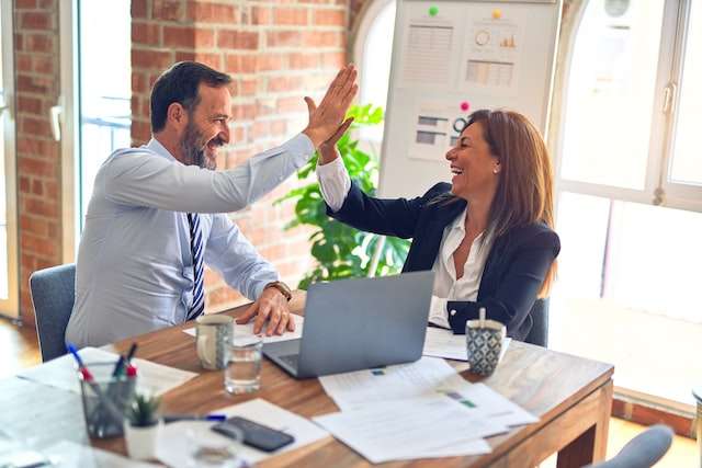 A businessman and woman high five, symbolic of eCommerce business advisory services.
