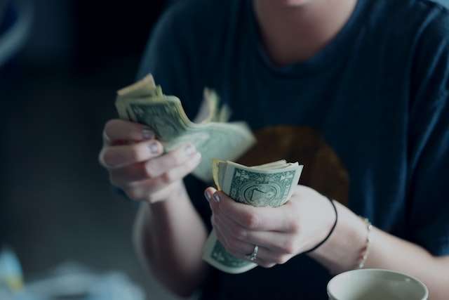 Two hands hold dollar bills, symbolic of our eCommerce payroll services.