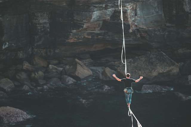 A man walks along rope across a cliff, symbolic of balance and therefore balance sheets.